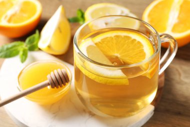 Cam fincanda aromatik meyve çayı, portakal, limon, bal ve nane. Masada, yakın plan.