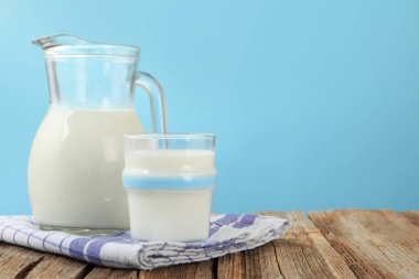 Açık mavi arka plana karşı ahşap masada taze süt, yakın plan. Metin için boşluk