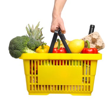 Beyaz arka planda farklı ürünleri olan alışveriş sepeti tutan adam, yakın plan.