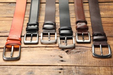 Ahşap masanın üstünde birçok farklı deri kemer var.