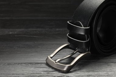 Ahşap masada siyah deri bir kemer, yakın plan. Metin için boşluk