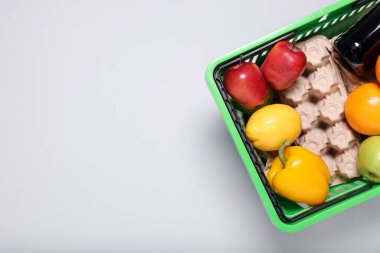 Işık arka planda ürünlerle dolu plastik alışveriş sepeti, üst manzara. Metin için boşluk