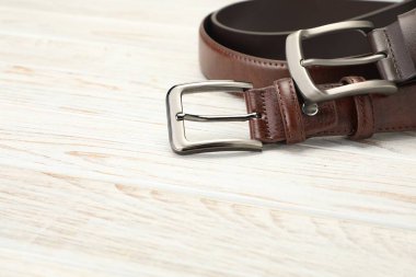Ahşap masada iki kahverengi deri kemer, yakın plan. Metin için boşluk