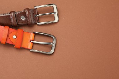 Soluk kahverengi arka planda iki deri kemer, düz uzanmış. Metin için boşluk