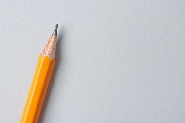 Gri arka planda keskin bir grafit kalem, üst manzara. Metin için boşluk