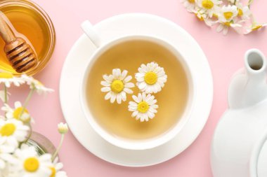 Fincanda nefis papatya çayı, taze çiçekler ve pembe arka planda bal, düz uzanma