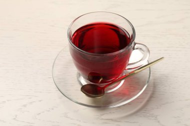 Cam fincanda leziz amber çayı ve açık tahta masada kaşık, yakın plan.