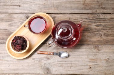 Cam fincanda leziz amber çayı, çaydanlık, kuru roselle sepals ve tahta masada kaşık, düz yatak. Metin için boşluk