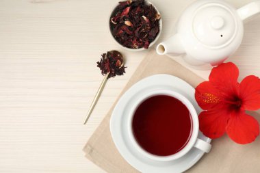 Fincanda leziz amber çayı, çaydanlık, kuru roselle sepals ve açık ahşap masa üzerinde çiçek, düz yatak. Metin için boşluk