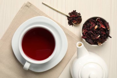 Fincanda leziz amber çayı, çaydanlık, kuru roselle sepals ve açık ahşap masada kaşık, düz uzanmış