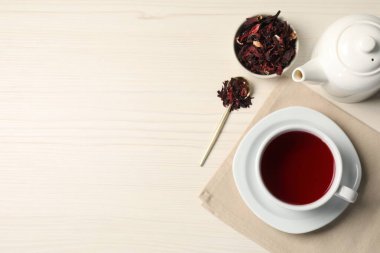 Fincanda leziz amber çayı, çaydanlık, kuru roselle sepals ve açık ahşap masada kaşık, düz yatak. Metin için boşluk