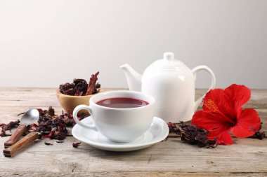 Lezzetli amber çayı fincanda, çaydanlıkta, kuru roselle sepals ve ahşap masada çiçek