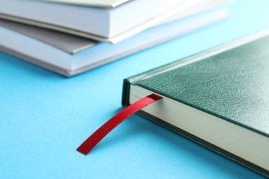 Kırmızı kurdele yer imi ve açık mavi arka planda renkli kitap, yakın plan