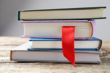 Kırmızı kurdele yer imi ve ahşap masadaki renkli kitap gri arkaplanda, yakın plan