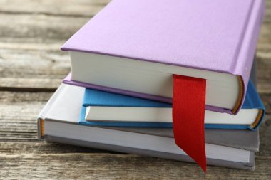 Kırmızı kurdele yer imi ve ahşap masa üzerinde renkli kitap, yakın plan.