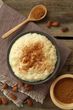 Tarçınlı lezzetli sütlaç ve ahşap masada badem.