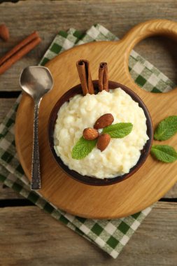 Tahta masada servis edilen bademli, nane ve tarçınlı lezzetli sütlaç.