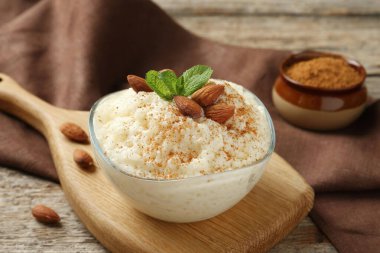 Tarçınlı lezzetli pirinç pudingi, ahşap masada nane ve badem, yakın plan.
