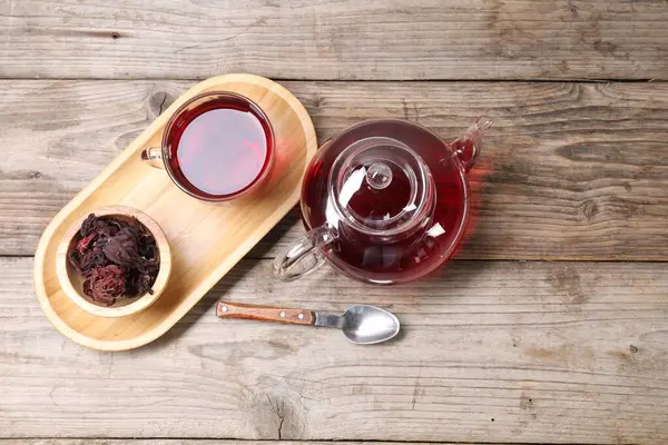 Cam fincanda leziz amber çayı, çaydanlık, kuru roselle sepals ve tahta masada kaşık, düz yatak. Metin için boşluk