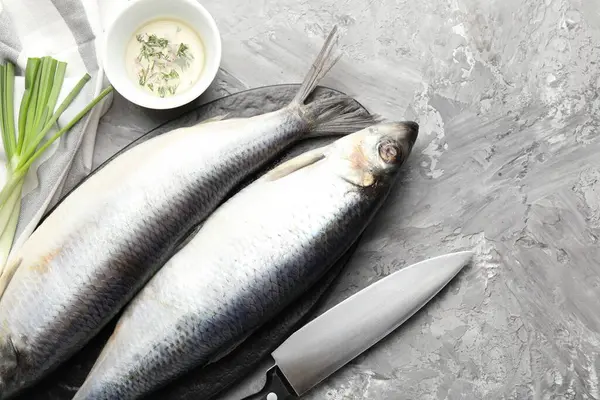 Tuzlu ringa balıkları, baharatlar ve bıçak gri masada, düz yerde. Metin için boşluk