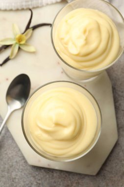 Lezzetli vanilyalı puding, kapsüller ve çiçek gri masada, düz uzanmış