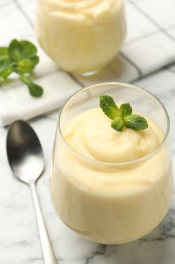 Beyaz mermer masada servis edilen naneli vanilyalı puding, yakın plan.