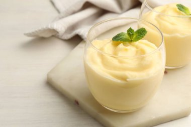 Beyaz ahşap masada naneli vanilyalı puding.