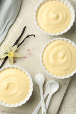 Kaşıklar, kapsüller ve çiçekli leziz vanilyalı puding.