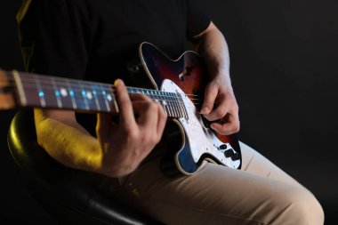 Siyah arka planda arabulucuyla gitar çalan adam, ele odaklan