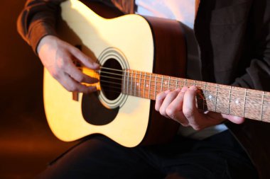 Kahverengi arka planda gitar çalan adam, yakın plan.