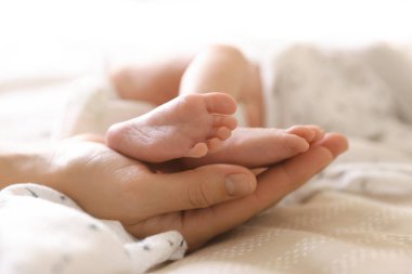 Anne, küçük bebeği evde, yatağında, yakın plan.