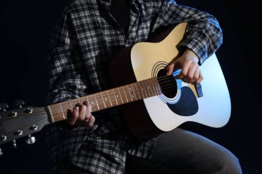 Siyah arka planda gitar çalan kadın, yakın plan