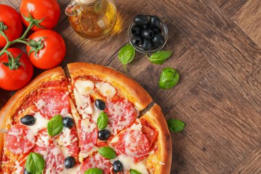 Lezzetli pizza ve malzemeler ahşap masada, düz yerde. Metin için boşluk