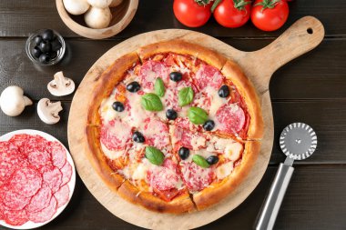 Lezzetli pizza, malzemeler ve siyah ahşap masa, düz uzanma
