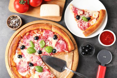 Lezzetli pizza ve malzemeler gri masada, düz yatıyordu.