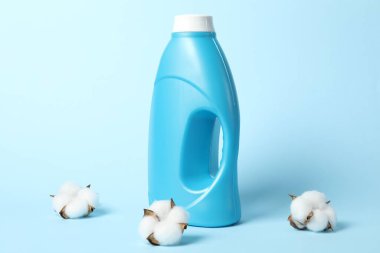 Bir şişe yumuşatıcı ve açık mavi arkaplanda pamuk çiçekleri.