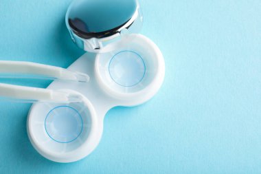 Temas lensleri ve açık mavi arka planda cımbız düz yerde. Metin için boşluk