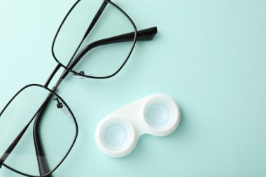 Kontakt lensler ve hafif turkuaz arka planda gözlük, düz konum