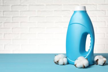 Beyaz tuğla duvara karşı açık mavi masada yumuşatıcı ve pamuk çiçekleri, metin için yer