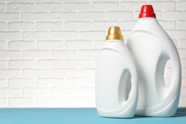 Açık mavi masada beyaz tuğla duvara karşı yumuşatıcı şişeler, metin için yer