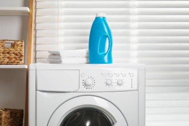 Bir şişe yumuşatıcı ve çamaşır makinesinin üzerindeki havlular.