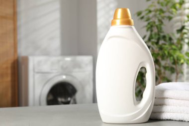 İçerideki açık gri masada yumuşatıcı ve havlu şişesi, metin için yer