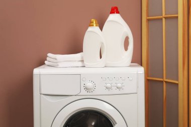 İçerideki çamaşır makinesinde yumuşatıcı ve havlu şişeleri.