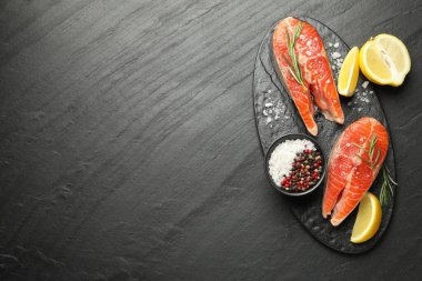 Deniz ürünleri. Somon bifteği, baharat ve limon siyah desenli masa, üst manzara. Metin için boşluk