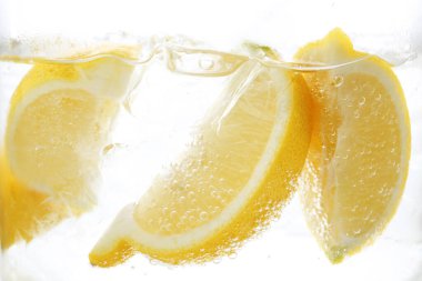 Beyaz arka planda limon dilimleri ile soda tazeleniyor, yakın plan.