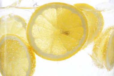 Beyaz arka planda limon dilimleri ile soda tazeleniyor, yakın plan.