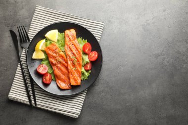 Çatal bıçak, marul, domates ve limonla servis edilen lezzetli ızgara somon balığı. Metin için boşluk