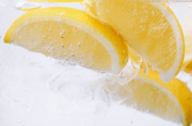 Beyaz arka planda limon dilimleri ve buzla soda tazeleniyor. Yakın plan.