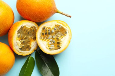 Açık mavi arka planda olgun sarı çarkıfelek meyveleri ve yaprakları düz yerde. Metin için boşluk