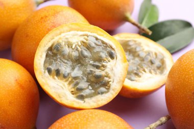 Olgun sarı çarkıfelek meyveleri ve yaprakları leylak arka planda, yakın plan